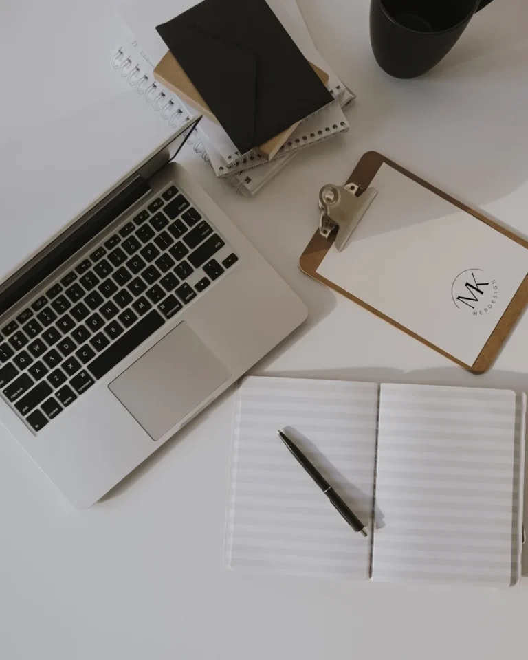 Aufgeräumter Schreibtisch mit Laptop, Notizbuch und MK Webdesign Logo als Symbol für eine klare Positionierung vor dem Website-Start